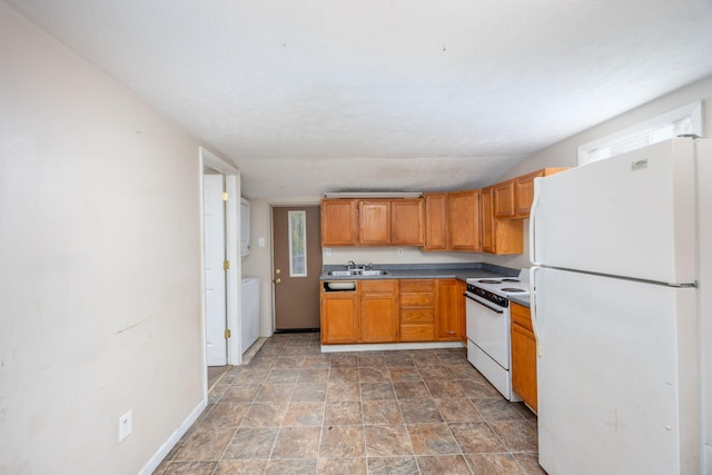 kitchen featuring white appliances, a textured ceiling, and sink