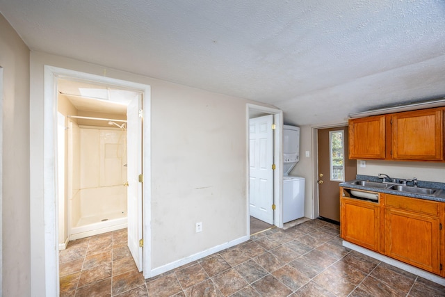 kitchen with stacked washing maching and dryer, a textured ceiling, and sink