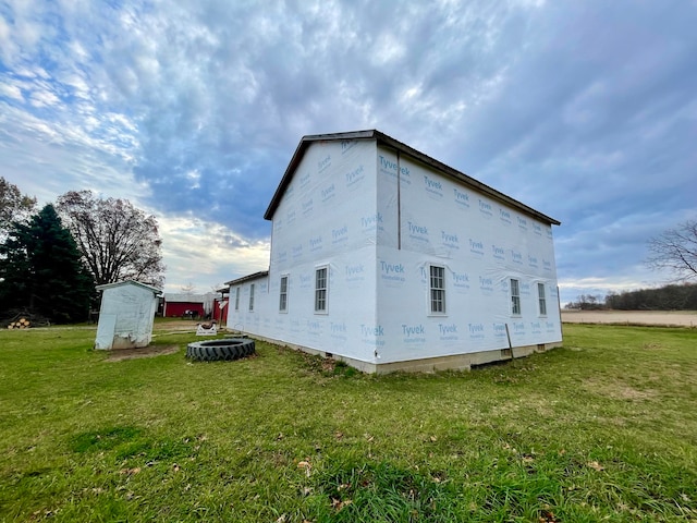 view of side of property featuring a lawn and a shed