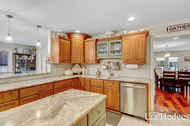 kitchen featuring sink, tasteful backsplash, light tile patterned floors, decorative light fixtures, and stainless steel dishwasher