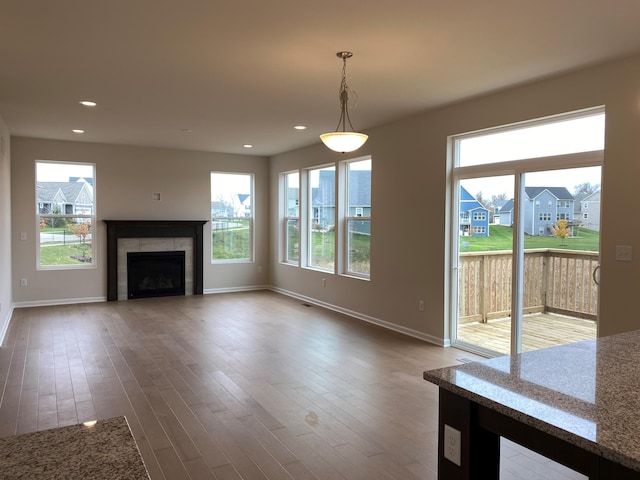 unfurnished living room with wood-type flooring and a tile fireplace