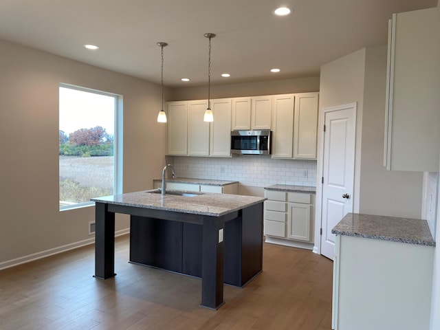 kitchen featuring white cabinetry, hardwood / wood-style floors, hanging light fixtures, and sink