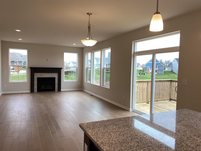 unfurnished living room featuring a tile fireplace, hardwood / wood-style flooring, and plenty of natural light