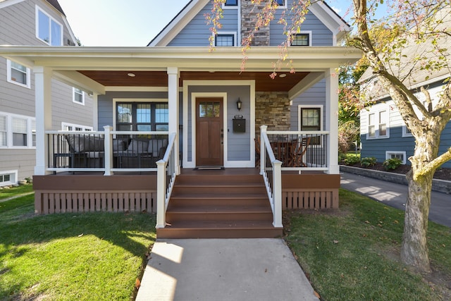 view of front of home featuring stone siding, a front yard, and covered porch