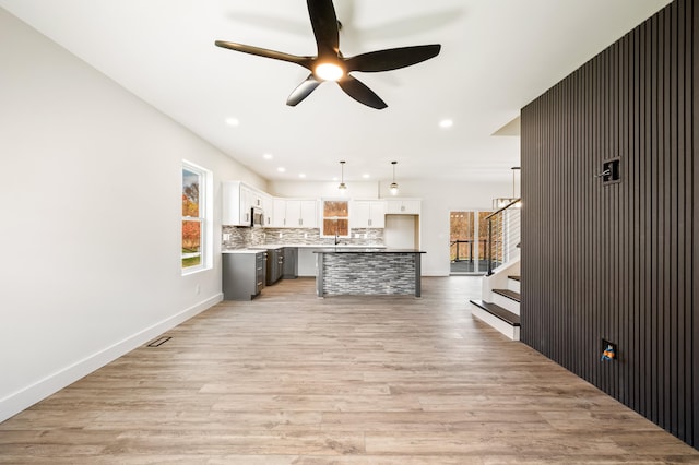 kitchen featuring a center island, ceiling fan, light wood-type flooring, decorative light fixtures, and white cabinetry