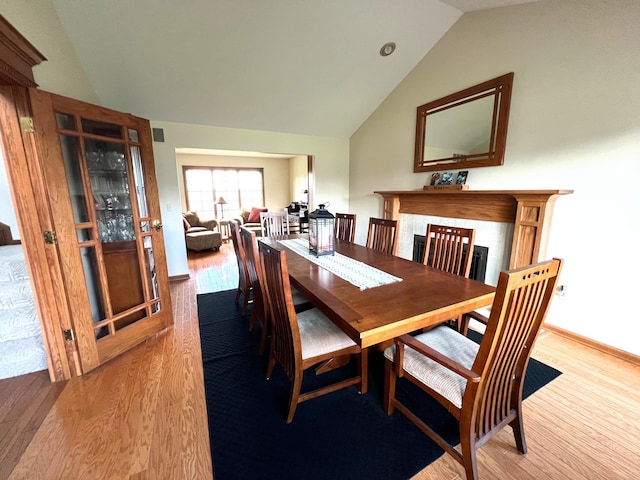 212 Saint Anne Ln, Monroe, MI 48162 - dining space featuring wood finished floors, vaulted ceiling, a fireplace, and baseboards