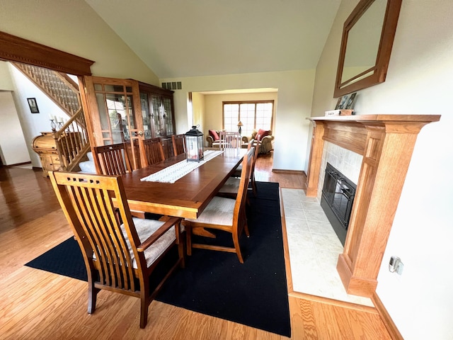 212 Saint Anne Ln, Monroe, MI 48162 - dining area featuring a tile fireplace, light wood-type flooring, baseboards, and high vaulted ceiling
