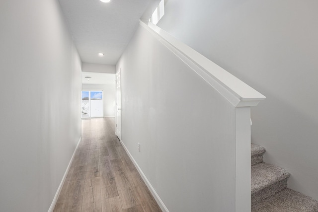 hall featuring light wood-style flooring, stairs, baseboards, and visible vents