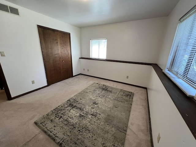 bedroom with a closet, multiple windows, and light carpet