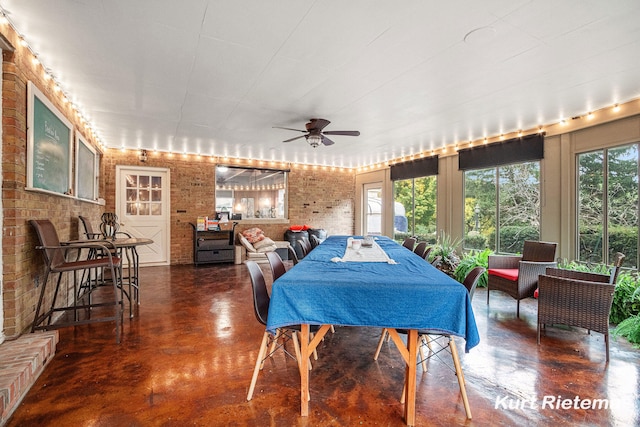 dining area with a wealth of natural light, ceiling fan, and brick wall