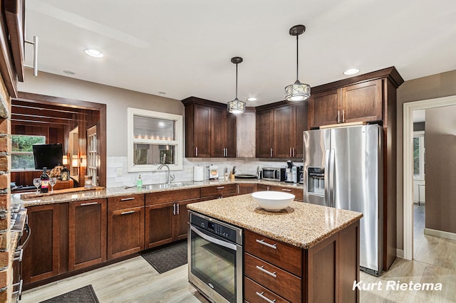 kitchen featuring light stone counters, stainless steel appliances, decorative light fixtures, dark brown cabinetry, and decorative backsplash