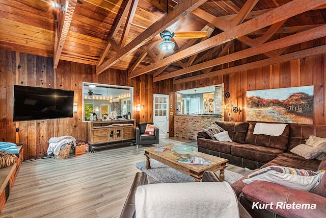 living room with lofted ceiling with beams, wood ceiling, wooden walls, and light hardwood / wood-style flooring