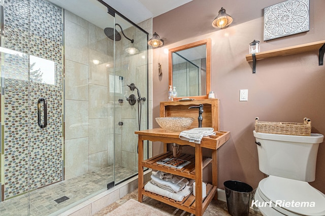 bathroom with an enclosed shower, sink, and toilet