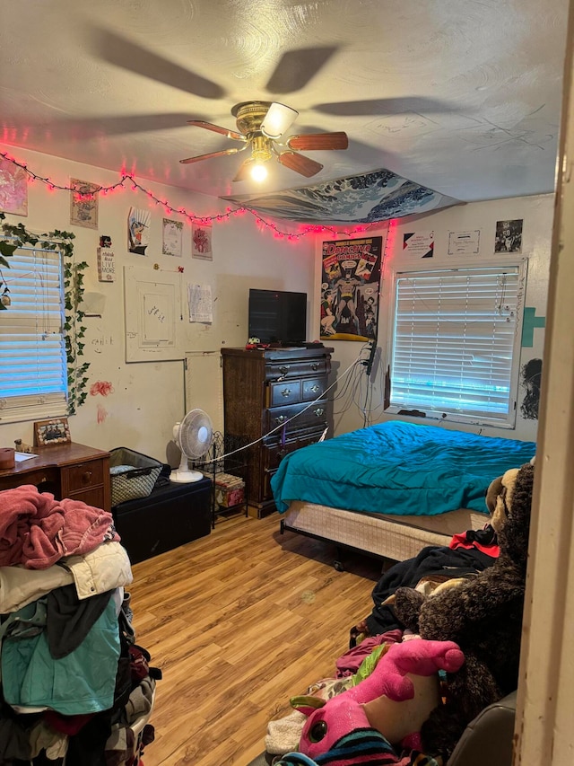 bedroom with ceiling fan, a textured ceiling, and wood-type flooring