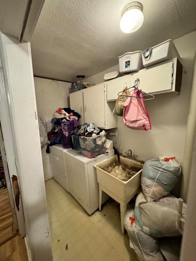 laundry area with cabinets, washing machine and dryer, and a textured ceiling