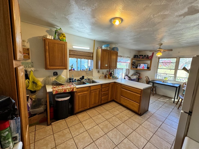 kitchen with sink, kitchen peninsula, ceiling fan, light tile patterned floors, and white fridge