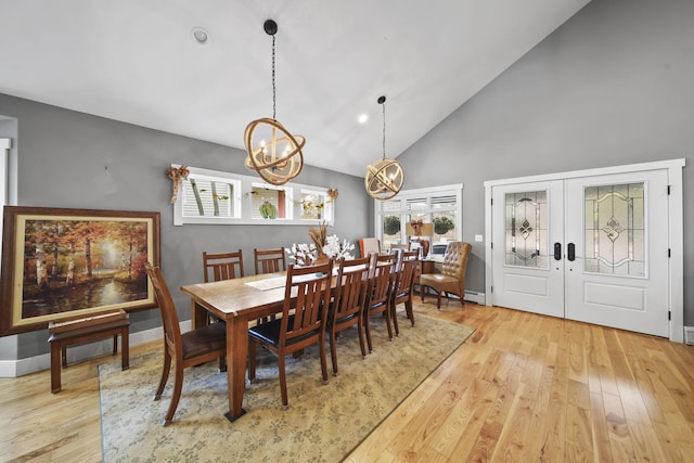 dining space with a notable chandelier, light wood-type flooring, high vaulted ceiling, and french doors