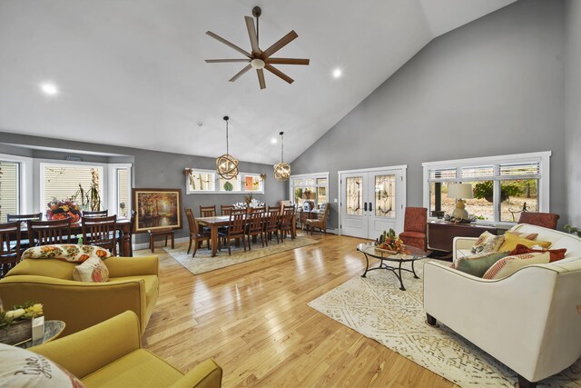 living room featuring ceiling fan, french doors, high vaulted ceiling, and light wood-type flooring