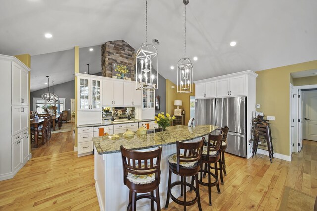 kitchen featuring white cabinets, a center island, stainless steel refrigerator, and light hardwood / wood-style flooring