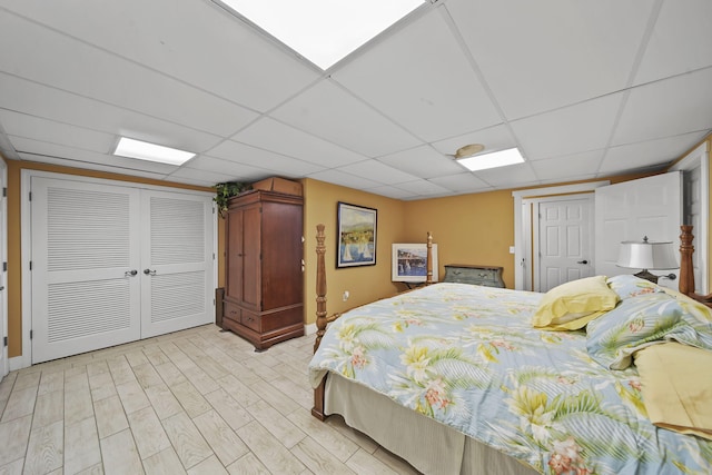 bedroom featuring a paneled ceiling, a closet, and light hardwood / wood-style flooring