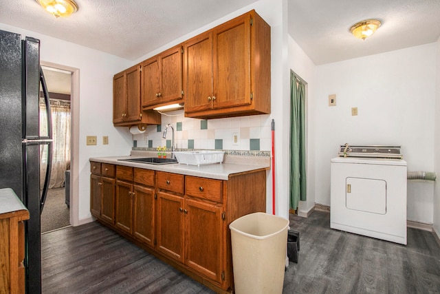 kitchen with sink, a textured ceiling, washer / dryer, black refrigerator, and dark hardwood / wood-style flooring