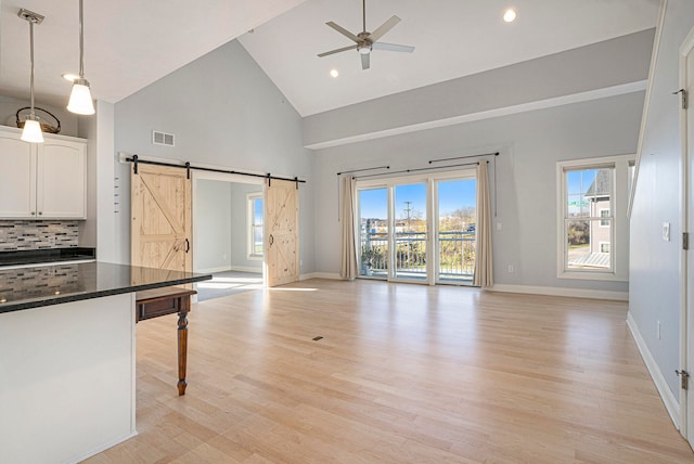 kitchen featuring white cabinetry, ceiling fan, high vaulted ceiling, hanging light fixtures, and a barn door