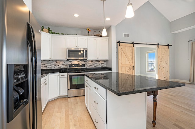 kitchen with a center island, a barn door, pendant lighting, light wood-type flooring, and appliances with stainless steel finishes