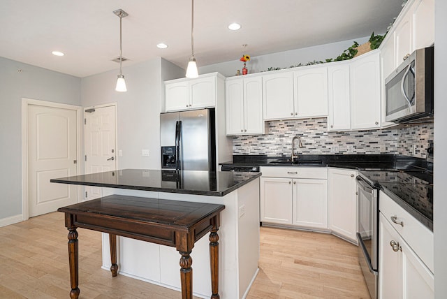 kitchen with stainless steel appliances, sink, pendant lighting, and light wood-type flooring