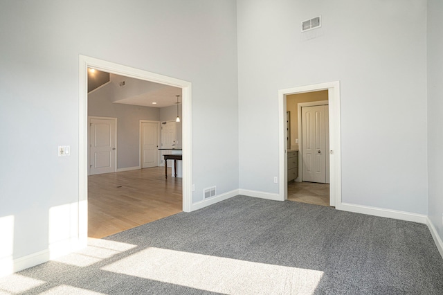 spare room with high vaulted ceiling and light carpet