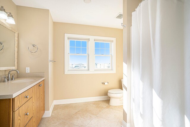 bathroom with toilet, vanity, and tile patterned floors