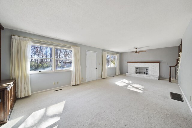 unfurnished living room with a textured ceiling, a fireplace, light carpet, and ceiling fan