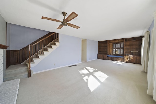 unfurnished living room featuring a brick fireplace, light colored carpet, and ceiling fan