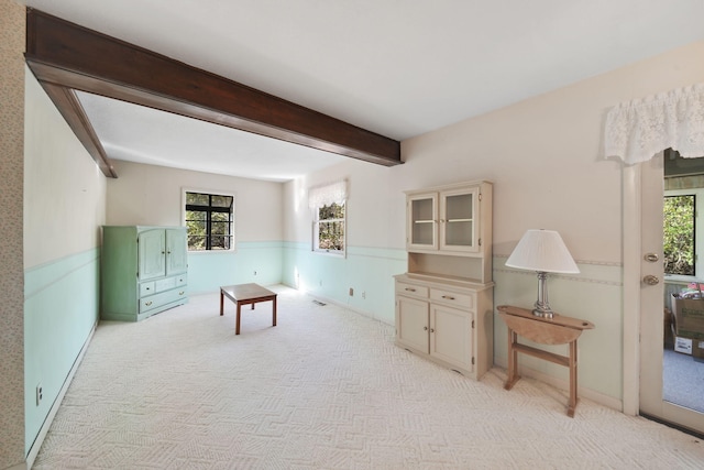 sitting room featuring light colored carpet and beam ceiling