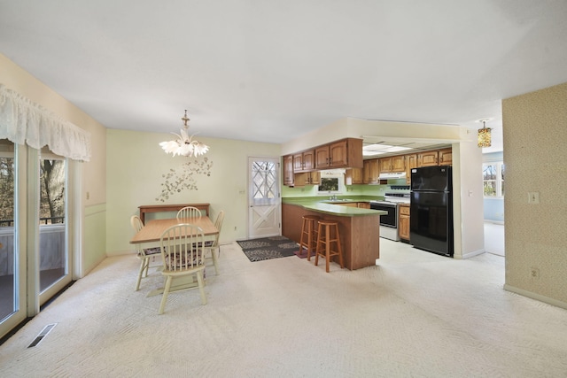 kitchen featuring black fridge, white electric stove, a breakfast bar, kitchen peninsula, and light colored carpet