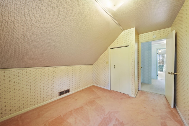 bonus room featuring a textured ceiling, carpet flooring, and lofted ceiling