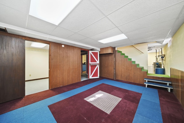 interior space with wood walls, a paneled ceiling, and gas water heater