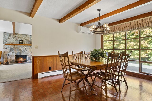 dining space featuring beam ceiling, baseboard heating, a wall unit AC, a chandelier, and a fireplace