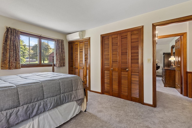 carpeted bedroom with a wall mounted AC and two closets