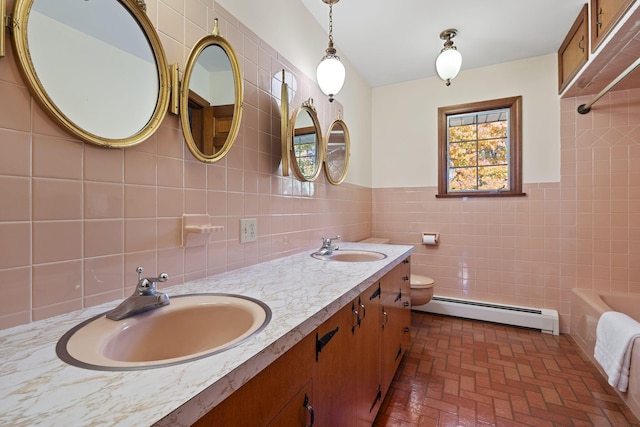 bathroom with a baseboard heating unit, toilet, a bathtub, vanity, and tile walls