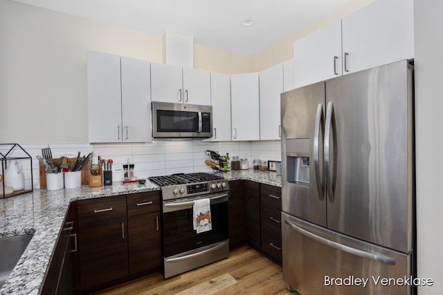 kitchen with white cabinets, dark brown cabinets, light hardwood / wood-style flooring, and appliances with stainless steel finishes