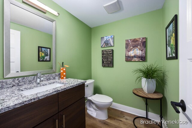 bathroom with hardwood / wood-style floors, vanity, and toilet