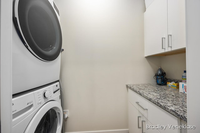 laundry area with cabinets and stacked washer and dryer