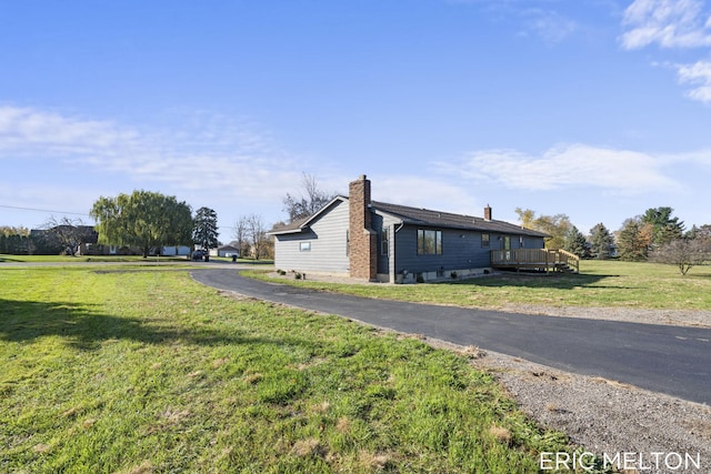 view of side of home with a wooden deck and a lawn