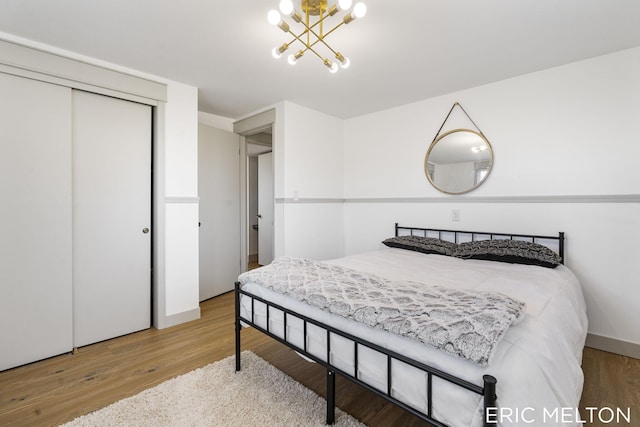 bedroom featuring a closet, an inviting chandelier, and wood-type flooring