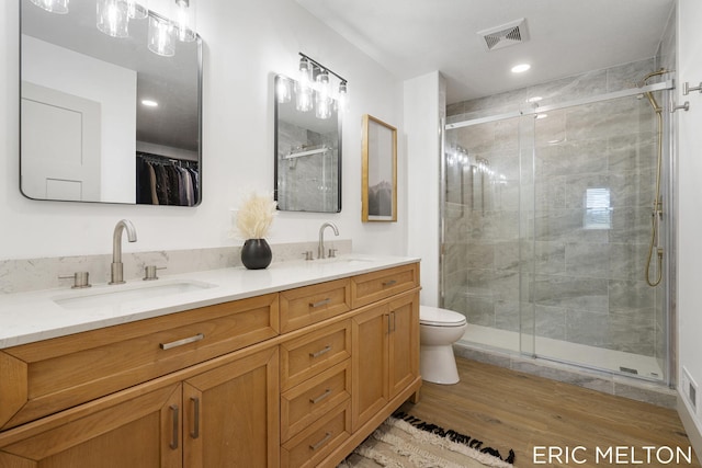 bathroom featuring vanity, hardwood / wood-style flooring, toilet, and a shower with shower door