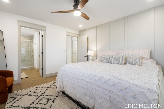 bedroom with light wood-type flooring, ceiling fan, and ensuite bath