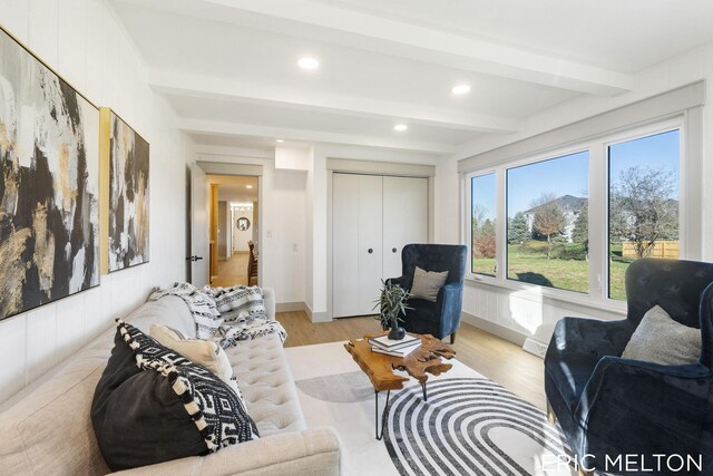 living room featuring beamed ceiling and light hardwood / wood-style floors