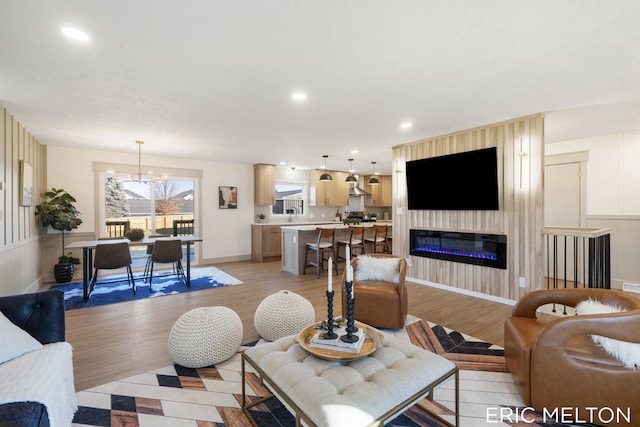 living room with an inviting chandelier, sink, and light hardwood / wood-style flooring