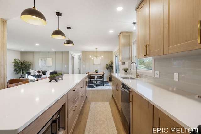 kitchen with light hardwood / wood-style floors, sink, light brown cabinets, hanging light fixtures, and dishwasher