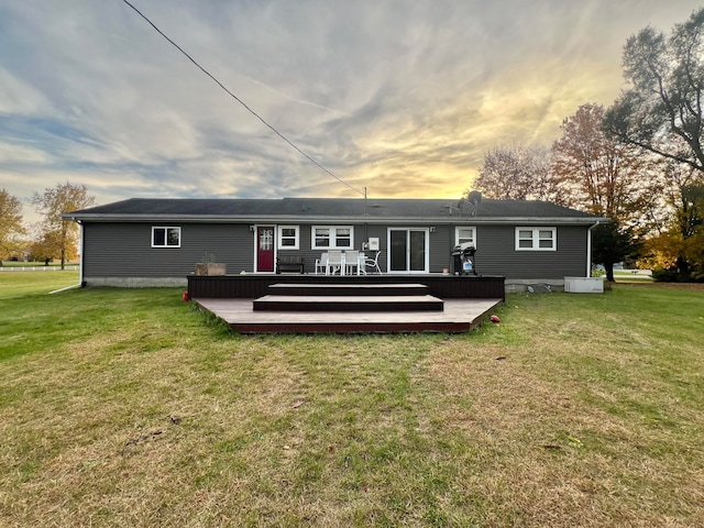 back house at dusk with central air condition unit, a wooden deck, and a yard